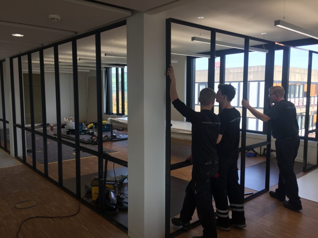 ein Bild von drei Mitarbeitern der Firma Vonhoegen, die einen Metallrahmen aufbauen